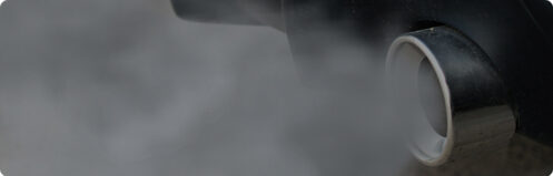 Close up of a car exhaust pipe blowing out smoke