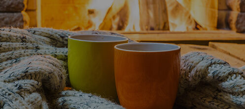 Coffee mugs on a cozy blanket in front of a wood fireplace