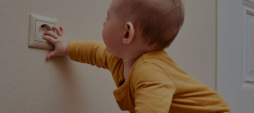 Baby sticking it's hand in a babyproofed electrical socket