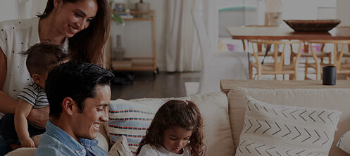Happy family sitting on couch with parents and young children