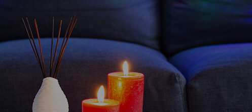 Couch with colorful Christmas lights behind a table with pretty festive candles