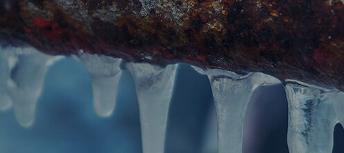 Frozen outdoor pipe with icicles hanging down