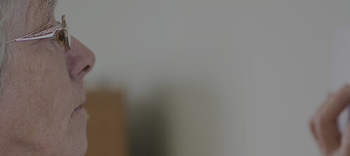 Elderly woman adjusting temperature on her thermostat