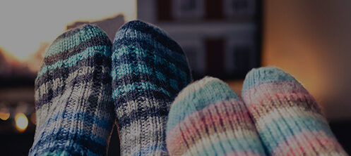 Close up of feet in colorful fuzzy socks propped up in front of a TV